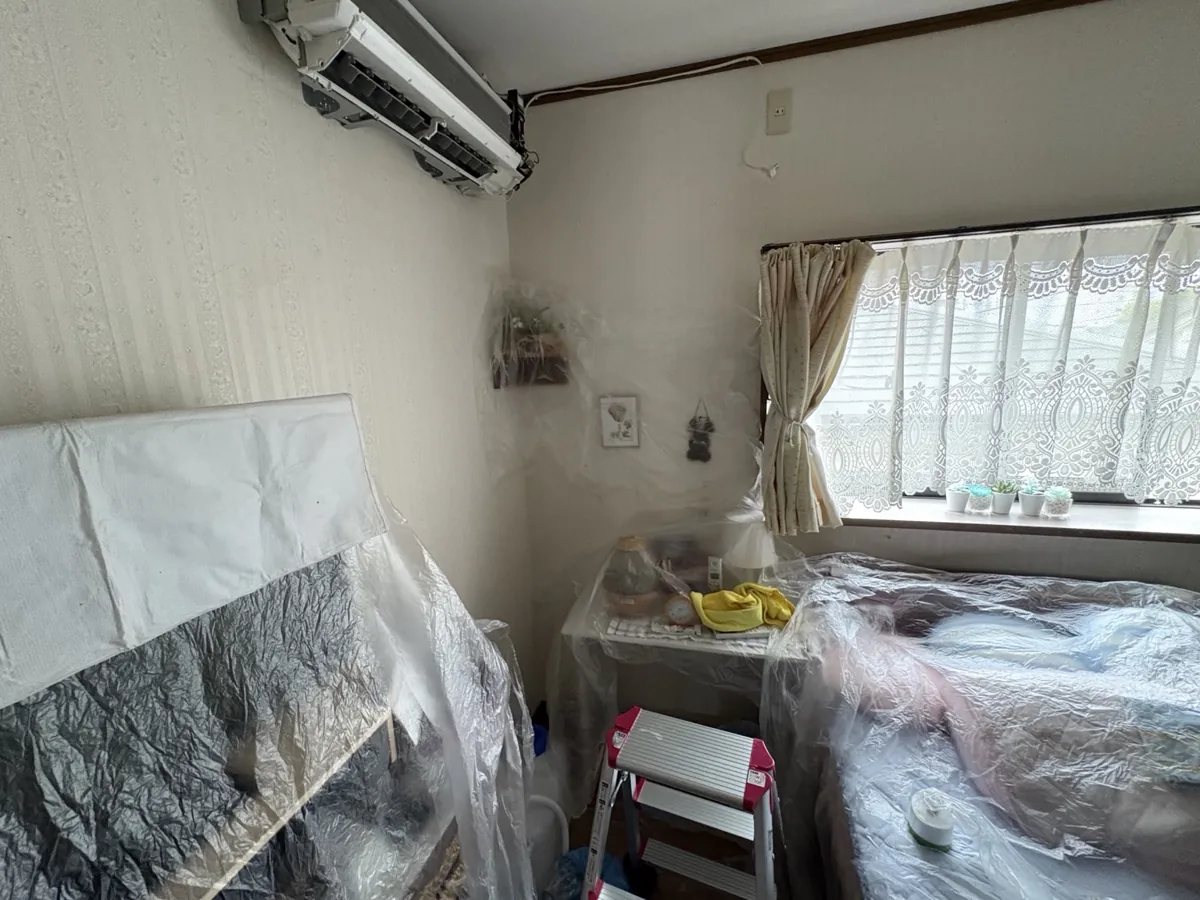 エアコン周辺の寝具や家具を広くシートで保護した室内