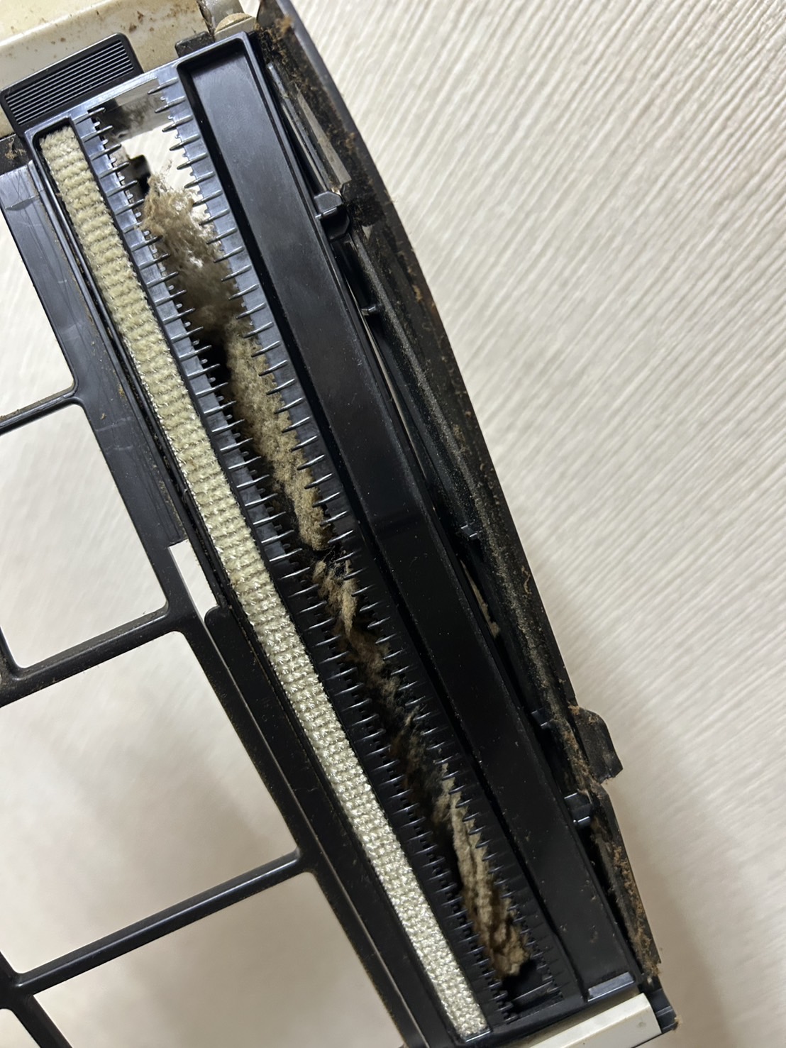 取り外した部品のブラシ周辺にたまったホコリ。四條畷市での清掃前の施工写真。
